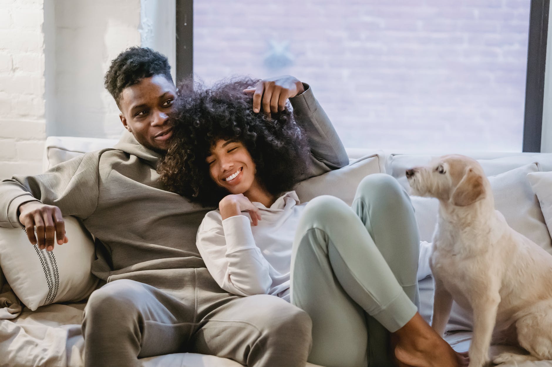 romantic black couple chilling on couch with dog